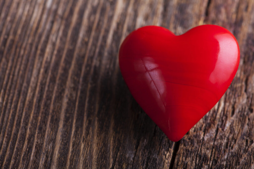 Red candy heart lying on a rustic wood plank