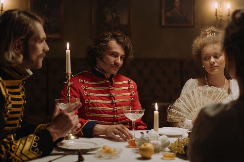 Woman and two men in period costume at a candlelit dinner